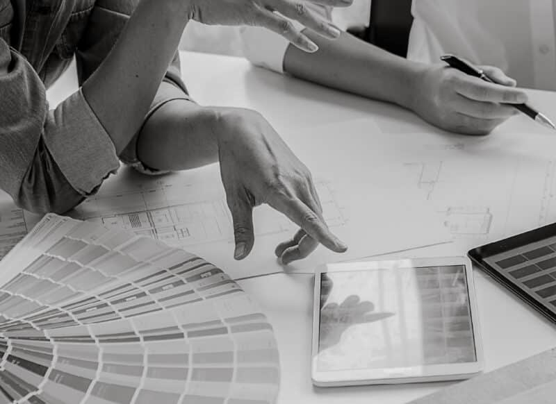 Team reviewing plans, finishes and digital layouts during a project design discussion.