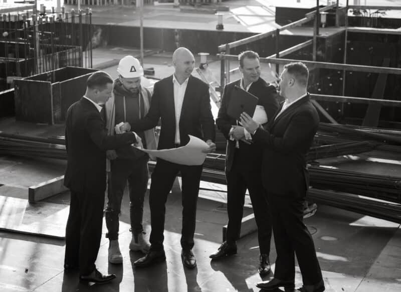 Project consultants and builders reviewing plans together on an active construction site.